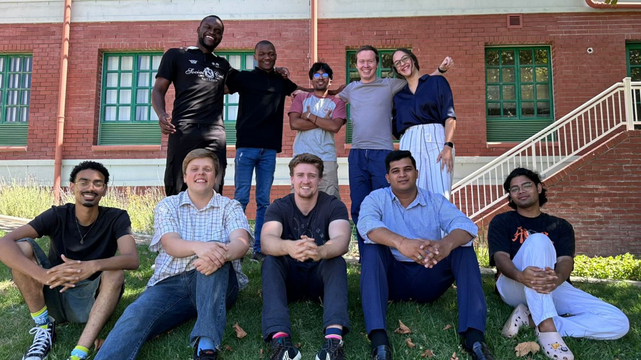 Photograph of the KRS interns of 2026 sitting outside a building and smiling at the camera